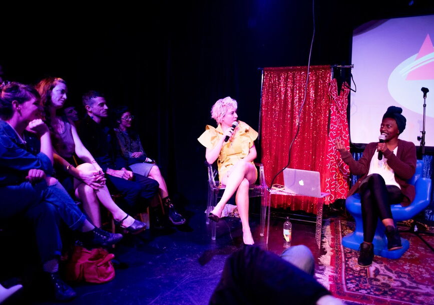 Photo of Christina Catherine Martinez, seated, in conversation with another woman, onstage in Aesthetical Relations.