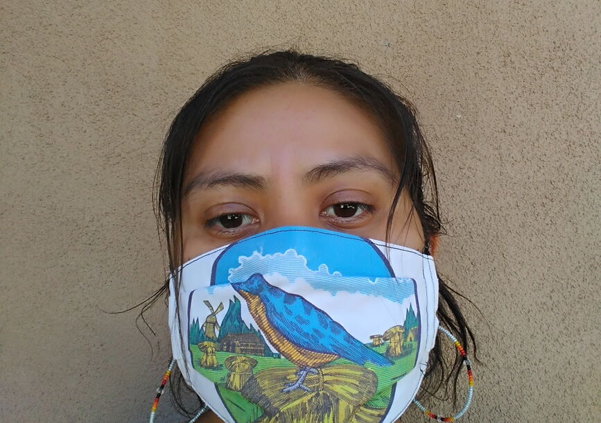 A woman's face is covered by a face mask with designs.