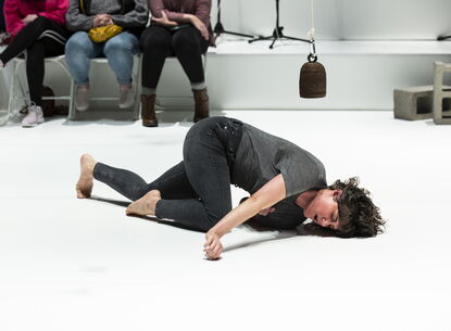 Faye Driscoll performing on a white floor.